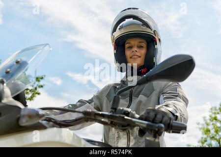 Fille est assise sur une moto et a un casque sur la tête Banque D'Images