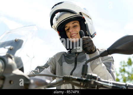 Fille est assise sur une moto et a un casque sur la tête Banque D'Images