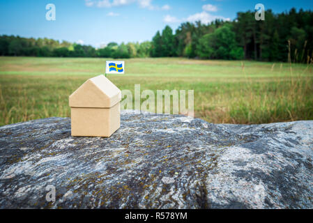 Petite maison en carton avec un drapeau suédois dans l'été scandinave paysage. Banque D'Images