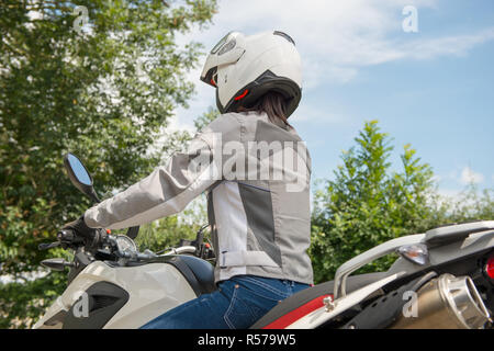 Fille est assise sur une moto et a un casque sur la tête Banque D'Images