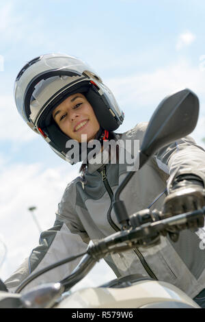 Fille est assise sur une moto et a un casque sur la tête Banque D'Images