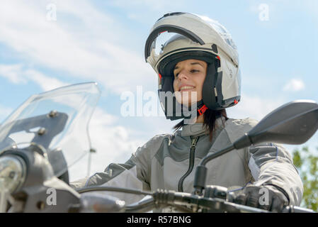 Fille est assise sur une moto et a un casque sur la tête Banque D'Images