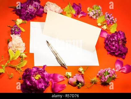 Fleurs, enveloppe et un stylo sur un fond rouge Banque D'Images