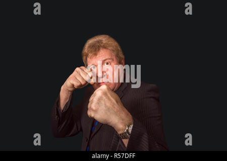 Studio shot of angry senior businessman with fist lever sur un fond sombre Banque D'Images