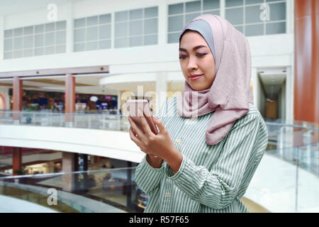 Jeune femme musulmane dans voile using mobile phone Banque D'Images