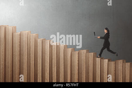 Young Asian businesswoman walking up on staircase with laptop Banque D'Images