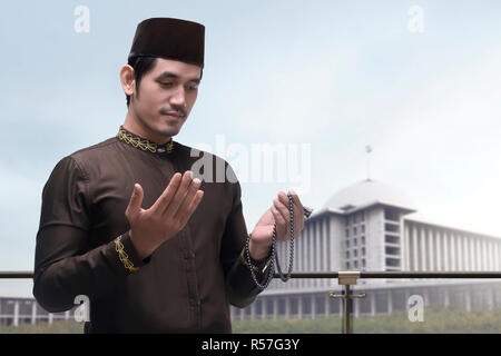 Portrait of Asian Muslim man raising hand et prier Banque D'Images