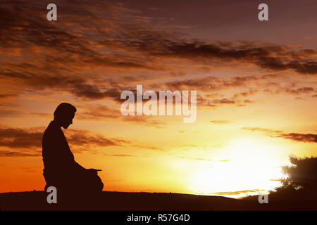 Silhouette d'asian musulman priant sur une colline Banque D'Images