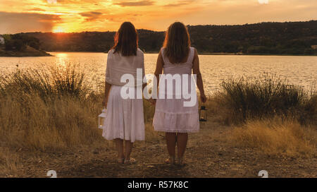 Deux femmes regardant le coucher du soleil avec robe blanche et de la lanterne sur le dos Banque D'Images