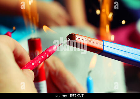 Une personne qui occupe de bougie d'anniversaire rose dans la main et l'allumer un briquet à essence Banque D'Images