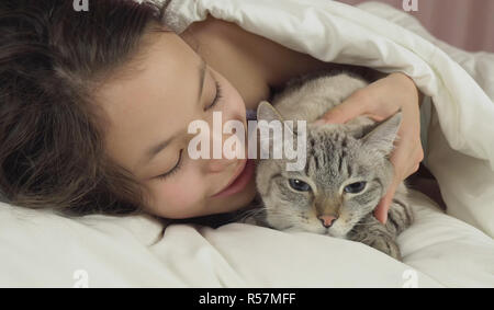 Happy teen girl baisers et des pourparlers avec Thai cat in bed Banque D'Images