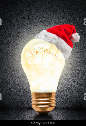 Ampoule Lumière rougeoyante wearing Santa hat avec Joyeux Noël message et copiez l'espace. Noël lumineux et d'un nouvelle année. Banque D'Images