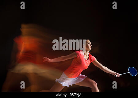 Jeune femme jouer au badminton sur fond noir Banque D'Images