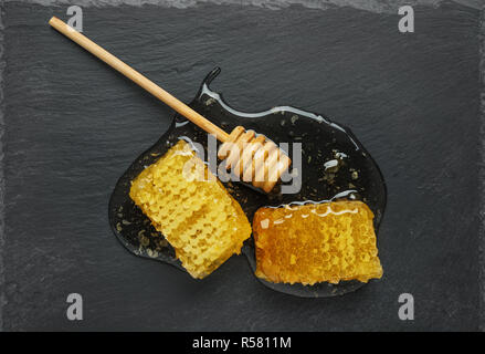 Nid d'or et de miel stick sur une plaque d'ardoise noire. Vue d'en haut Banque D'Images