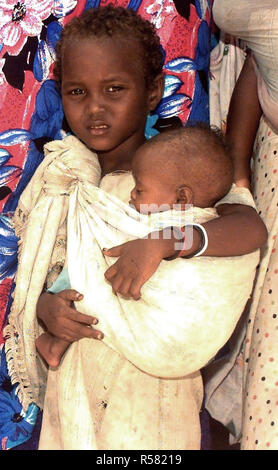 1993 - tout droit, medium close-up d'une jeune fille somalienne, berçant sa sœur en sangle qui est liée à l'épaule. Ils attendent en ligne pour voir les médecins de la Marine américaine à un programme d'action civique médicale dans la capitale de Mogadiscio, en Somalie. Banque D'Images