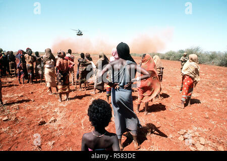 1993 - Les villageois regardent un escadron d'hélicoptères lourds Marine 363 (HMH-363) CH-53D Sea Stallion helicopter décollera après la livraison d'un chargement de grain au cours de l'effort de secours multinationales l'opération RESTORE HOPE. Banque D'Images