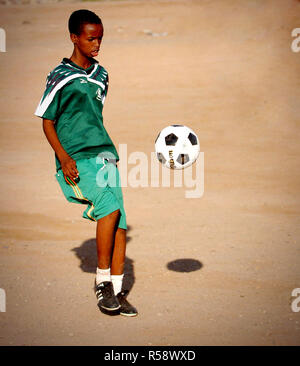 Un garçon de la ville de Djibouti orphelinat du garçon un ballon de soccer coups donnés par les membres de l'armée américaine déployés avec la Force opérationnelle interarmées - Corne de l'Afrique (CJTF-HOA). - Corne de l'Afrique est une unité de commandement central des États-Unis qui mène des opérations et de la formation pour aider les pays partenaires à lutter contre le terrorisme afin d'établir un environnement sûr et permettre à la stabilité régionale. Banque D'Images