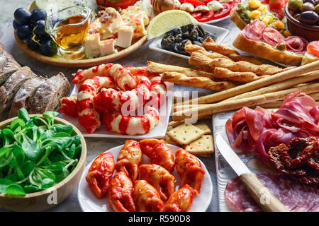 Antipasti italiens des en-cas. Brushettas, variété de fromages, crevettes, saumon, les olives, le prosciutto avec poire, de salami et de jambon sur table, top gris grunge Banque D'Images