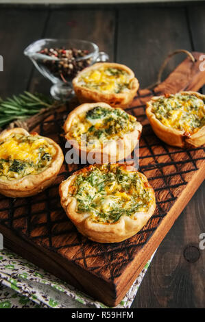 Mini quiches salés sur une planche de bois. Pâte feuilletée pâtés sur une woo Banque D'Images