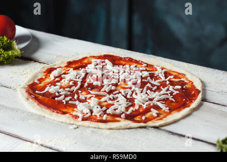 Libre de matières premières fait maison avec du fromage à pizza et de la sauce tomate sur un fond de bois Banque D'Images