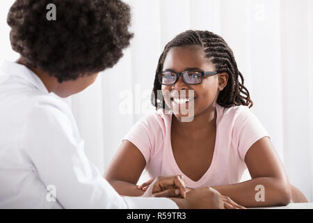 Smiling Girl Wearing Eyeglasses en face d'optométriste Banque D'Images