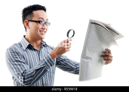 Asian man reading newspaper avec loupe Banque D'Images