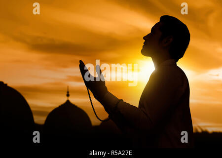 Silhouette d'Asian Muslim man raising hand et prier Banque D'Images