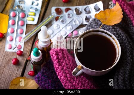 L'automne et les soins de santé. tasse de thé, pilules et thermomètre on a wooden background Banque D'Images