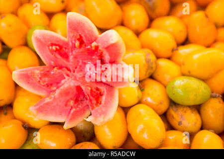 Juicy Fruit de goyave rose affiche se trouve sur un lit de fruits jaune vif à un siriguela marché de producteurs tropicaux à Rio de Janeiro, Brésil Banque D'Images