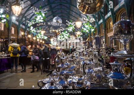 Londres - le 26 novembre 2018 : clients de vacances parcourir affiche d'antiquités en vertu de l'arches de style néoclassique de la pomme Marché à Covent Garden. Banque D'Images