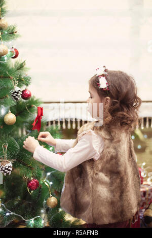 Petit enfant girl decorating Christmas Tree avec des boules à la maison, à l'intérieur. Close up. Concept de Noël. Banque D'Images