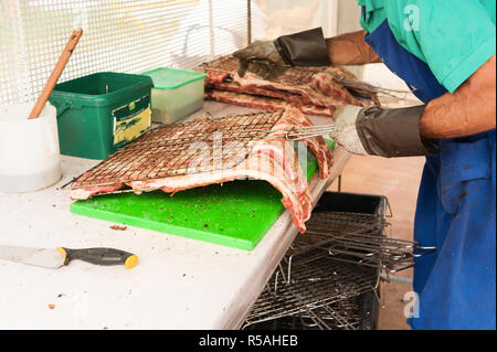 Cuisinier prépare la viande à rôtir sur le gril. Banque D'Images