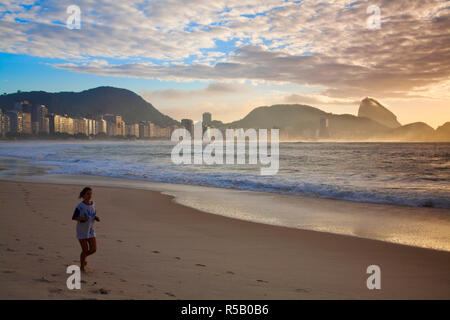 Brésil, Rio de Janeiro, Jogger sur la plage de Copacabana, au lever du soleil à la recherche vers le Pain de Sucre Banque D'Images