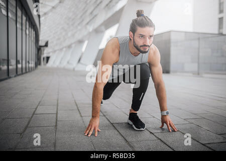 Photo de jeune homme prêt à exécuter. Il est en position de sprint et regarder en direction de l'avant. Guy est prêt à courir vite. Il est solide et bien construit Banque D'Images