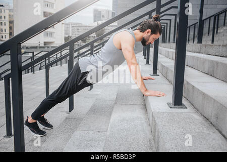 Photo de l'exercice sportif bien construite sur les mesures. Il est en position de planches et regarde vers le bas. Guy est calme et concentré. Il est seul il y Banque D'Images