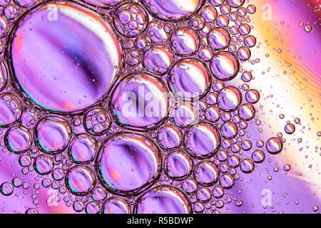 Résumé fond de close up detail dans de l'huile végétale gouttelettes/bulles sur la surface de l'eau avec un fond coloré Banque D'Images