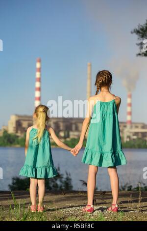 Mère et fille à la cheminée de l'usine de piles à un air pollution Banque D'Images
