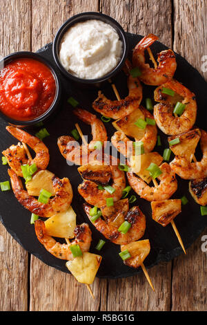 Brochette de crevettes épicées avec de l'ananas servi avec deux sauces sur la table. Haut Vertical Vue de dessus Banque D'Images