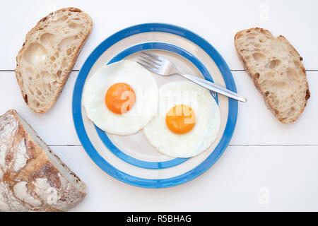 Les oeufs de poules frit sur un cornishware plaque avec du pain au levain Banque D'Images