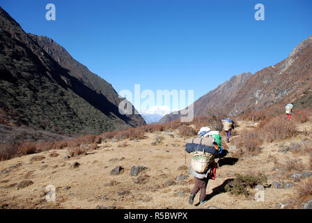 Porteurs descendent une vallée escarpée dans le haut Himalaya du Népal oriental Banque D'Images