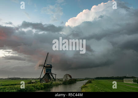 Paysage hollandais avec moulin le long d'un canal et stormclouds en arrière-plan. Derrière une tempête le ciel dégagé et le paysage était magnifique allumé Banque D'Images