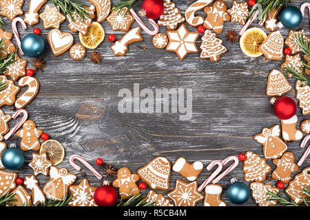 Cadre de Noël faite de biscuits au gingembre, d'anis étoile, baies, canne de Noël sucettes, boules de Noël, l'orange et romarin chips sur fond de bois. Mise à plat. Banque D'Images