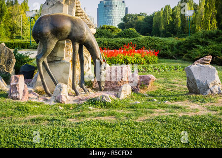 19 septembre 2017, Bucarest/Roumanie - Statue d'un cerf dans le parc Herastrau, immeuble de bureaux à l'arrière-plan Banque D'Images