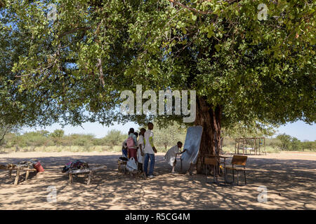 Groupe d'enfants d'étudier sous un arbre dans une école rurale. Banque D'Images