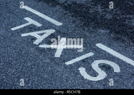 Enseigne sur un taxi peint en lettres blanches sur la route goudronnée. Banque D'Images