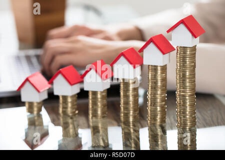 Maisons miniatures au-dessus de la pile de jetons sur la table en bois Banque D'Images