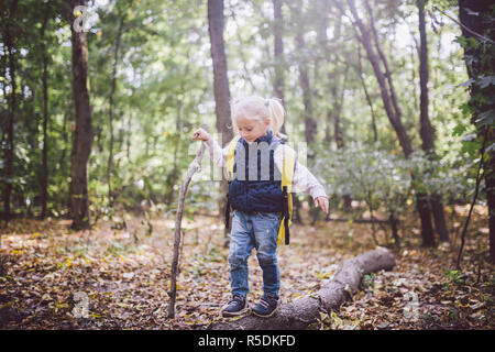 Thème activités de plein air dans la nature. Drôle de petit fille blonde caucasienne promenades promenades randonnées en forêt sur terrain accidenté avec un grand sac à dos. Utilise w Banque D'Images