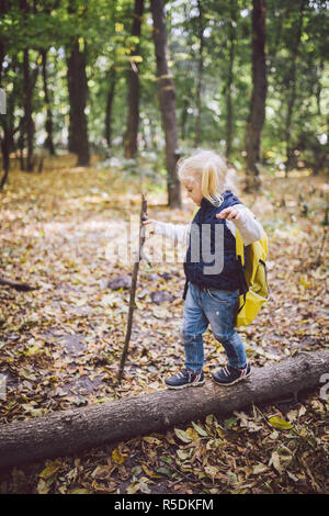 Thème activités de plein air dans la nature. Drôle de petit fille blonde caucasienne promenades promenades randonnées en forêt sur terrain accidenté avec un grand sac à dos. Utilise w Banque D'Images