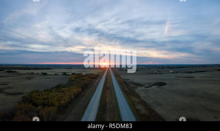 Vue Aérienne Vue panoramique de la route dans les Prairies au cours d'une vibrante nuageux coucher du soleil. Pris à l'est d'Edmonton, Alberta, Canada. Banque D'Images