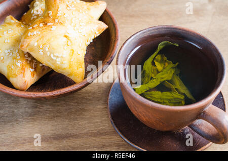 Du thé vert et de pâtés sur table en bois rustique. Concept petit-déjeuner. Banque D'Images